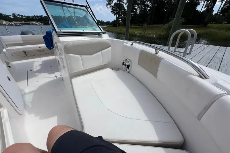 Slide: The Image of 2015 Robalo R227 Dual Console boat interior with white seating and dock view. - 23