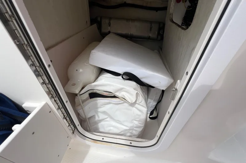 Slide: The Image of Storage compartment in a 2015 Robalo R227 Dual Console boat with cushions and gear. - 25