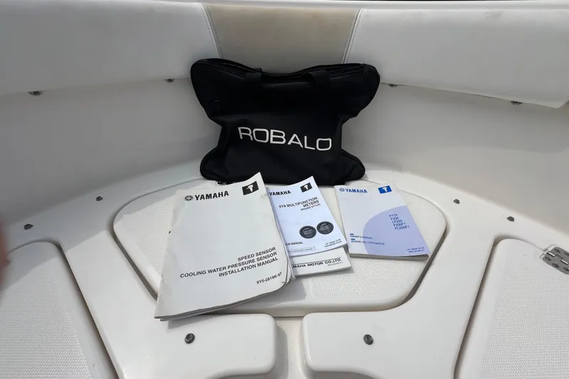 Slide: The Image of 2015 Robalo R227 Dual Console manuals and bag on boat seat. - 32
