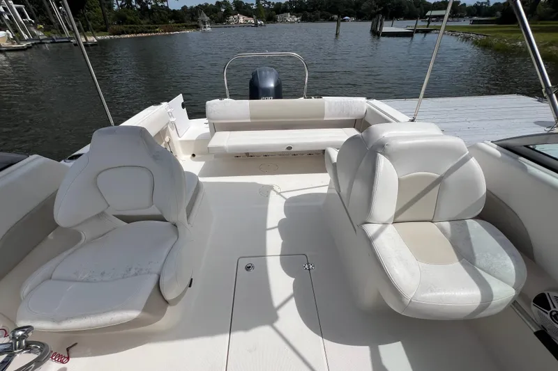 Slide: The Image of 2015 Robalo R227 Dual Console boat interior with white seating, docked by a serene lake. - 34