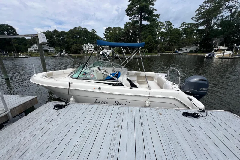 Slide: The Image of 2015 Robalo R227 Dual Console boat docked by a serene lakeside. - 4