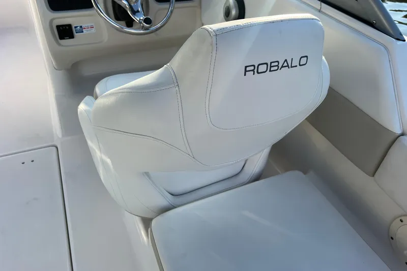 Slide: The Image of 2015 Robalo R227 Dual Console boat interior with white seating and steering wheel. - 57