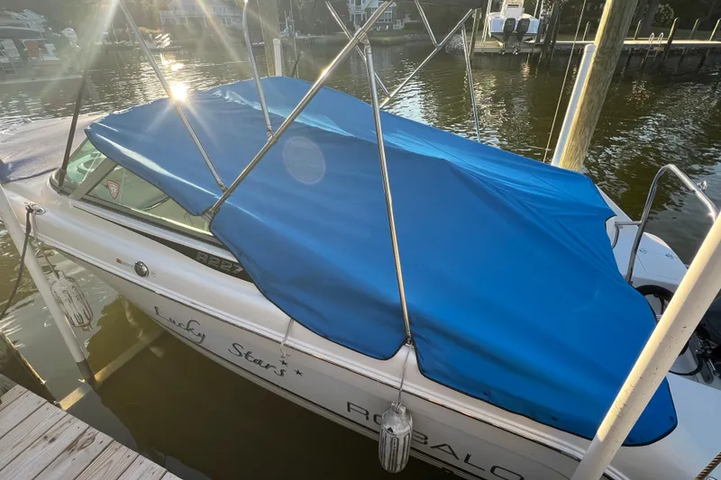 Slide: The Image of 2015 Robalo R227 Dual Console boat with blue cover docked by the water. - 64