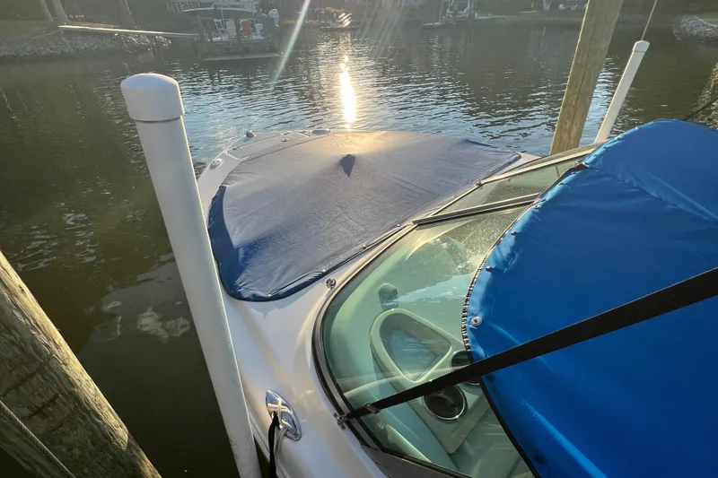 Slide: The Image of 2015 Robalo R227 Dual Console boat docked with blue covers, sun reflecting on water. - 65