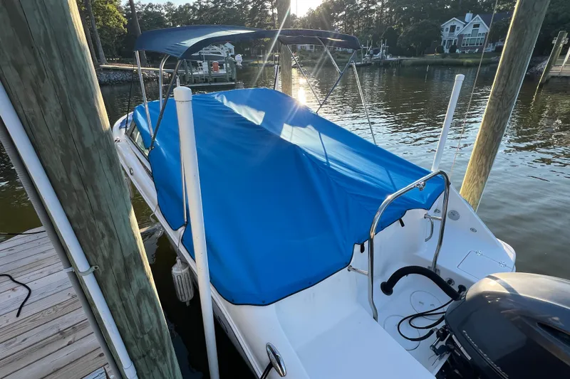 Slide: The Image of 2015 Robalo R227 Dual Console boat with blue cover docked by the water. - 67