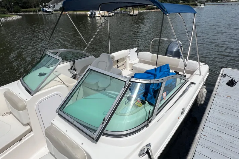 Slide: The Image of 2015 Robalo R227 Dual Console boat docked, featuring a blue canopy and spacious seating. - 8