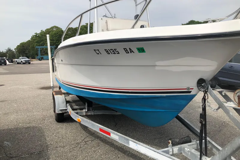 Slide: The Image of 1991 Four Winns 217 Quest boat on trailer, white with blue hull, parked outdoors. - 13