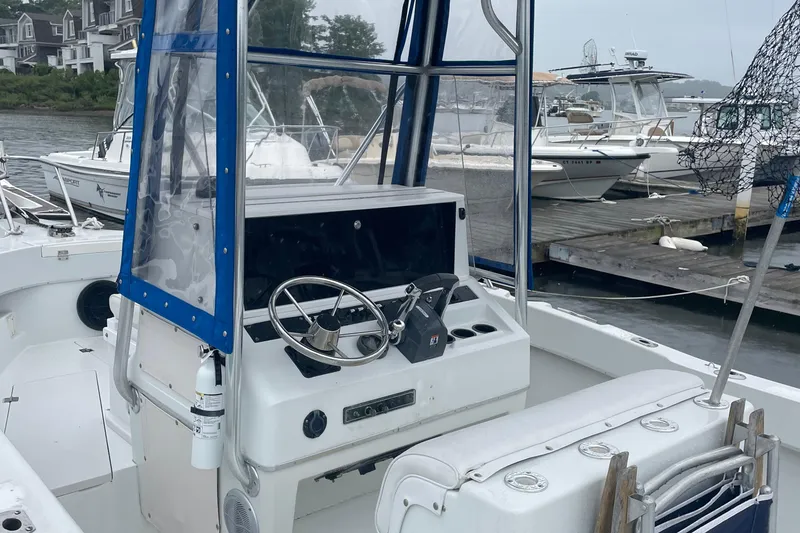 Slide: The Image of 1991 Four Winns 217 Quest boat interior with steering wheel and docked boats in background. - 3