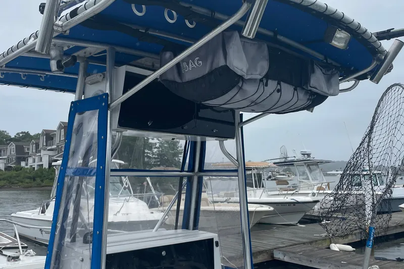 Slide: The Image of 1991 Four Winns 217 Quest boat docked, featuring a blue canopy and fishing net. - 7