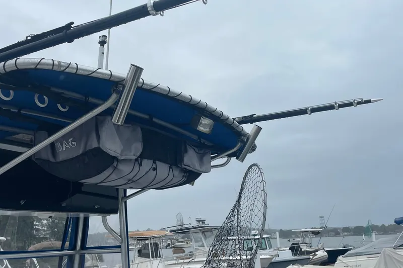 Slide: The Image of 1991 Four Winns 217 Quest boat with fishing gear and net, docked under cloudy skies. - 8