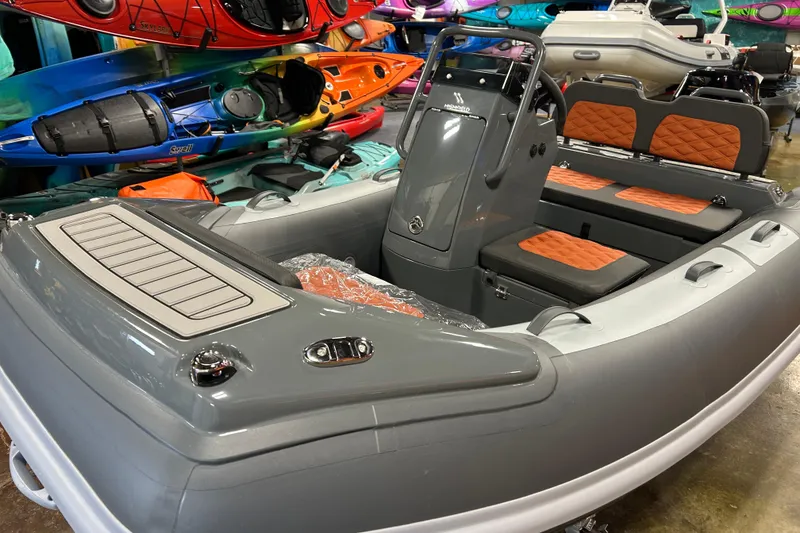 Slide: The Image of 2026 Highfield Sport 330 inflatable boat with orange seats, displayed indoors. - 2