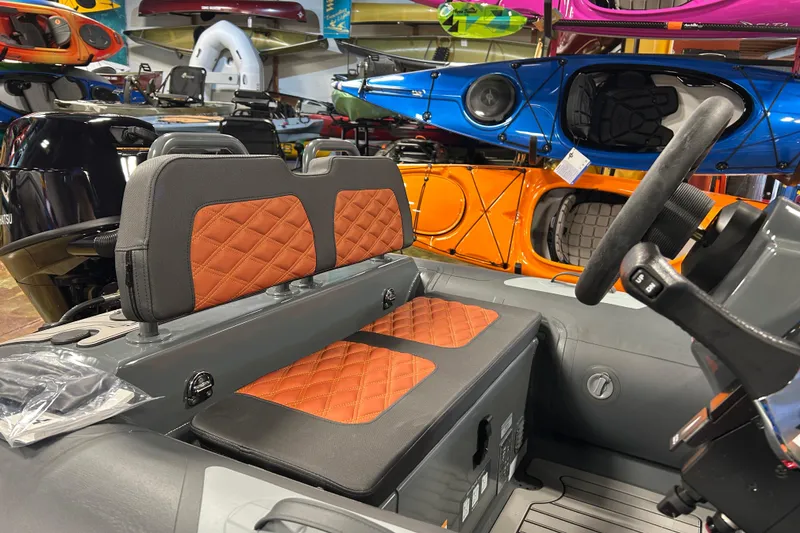 Slide: The Image of 2026 Highfield Sport 330 boat interior with orange quilted seats, surrounded by colorful kayaks. - 8
