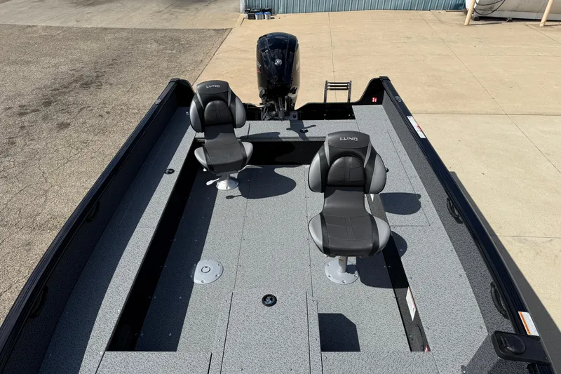 Slide: The Image of 2026 Lund 1800 Explorer Tiller boat with dual seats and outboard motor, docked on concrete. - 12