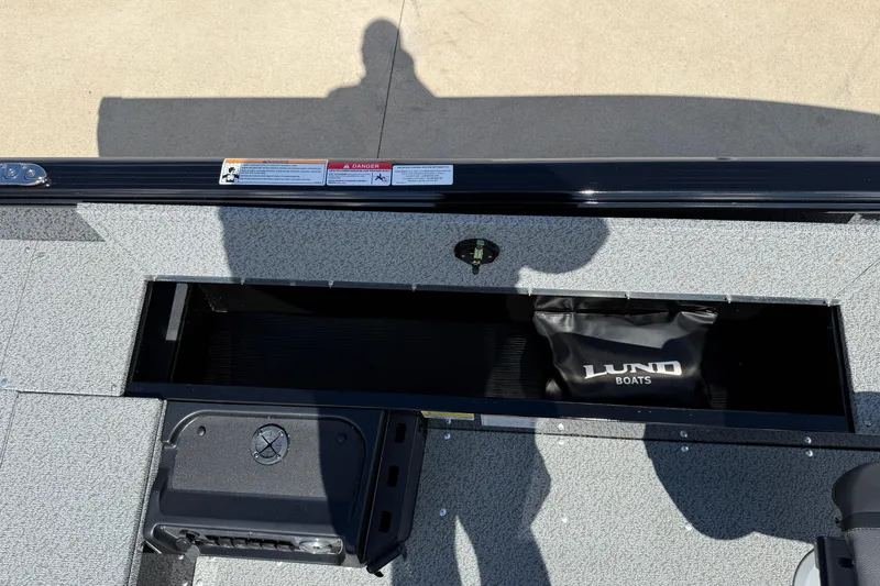 Slide: The Image of 2026 Lund 1800 Explorer Tiller boat interior with storage compartment and Lund bag. - 17