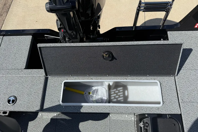 Slide: The Image of 2026 Lund 1800 Explorer Tiller boat storage compartment with fishing net and equipment. - 20