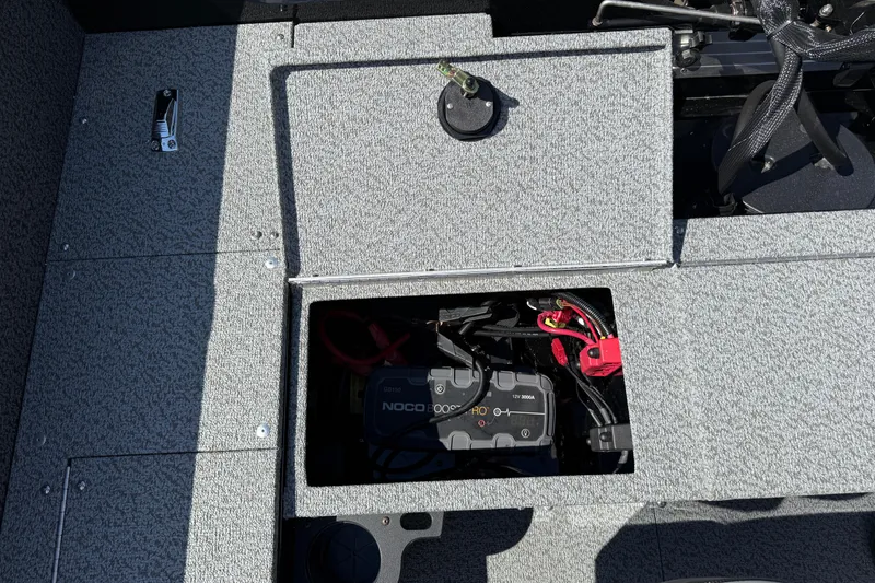 Slide: The Image of 2026 Lund 1800 Explorer Tiller boat battery compartment with NOCO charger visible. - 21