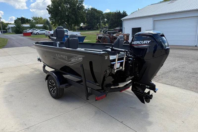 Slide: The Image of 2026 Lund 1800 Explorer Tiller boat with Mercury engine on trailer, parked outdoors. - 5