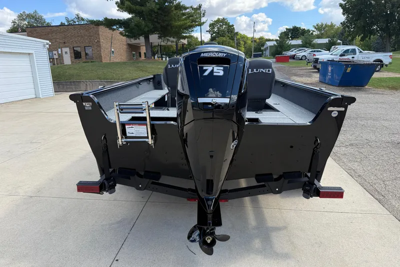 Slide: The Image of 2026 Lund 1800 Explorer Tiller boat with Mercury 75 engine, parked outdoors. - 6