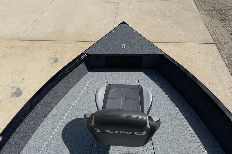 Slide: The Image of 2026 Lund 1800 Explorer Tiller boat interior with a single seat on a concrete surface. - 9