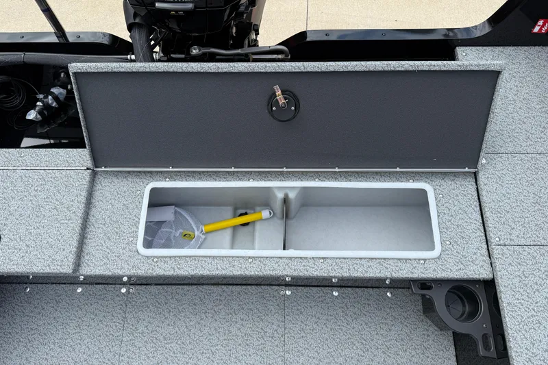 Slide: The Image of 2026 Lund 1800 Explorer Sport boat storage compartment with fishing net and handle. - 24
