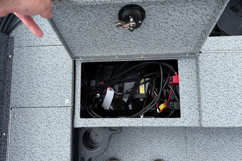 Slide: The Image of Open storage compartment in 2026 Lund 1800 Explorer Sport boat, showing battery and wiring. - 25