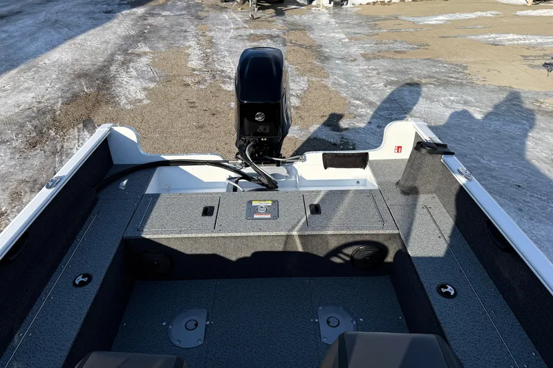 Slide: The Image of 2026 Lund 1650 Rebel XL SS boat interior with motor, parked on icy ground. - 18