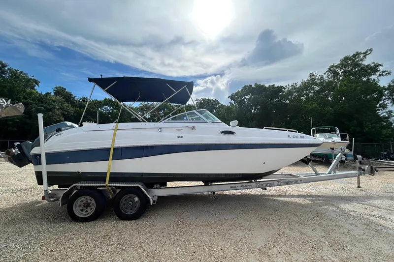 Slide: The Image of 2004 Hurricane SD 260 boat on trailer, parked outdoors under a cloudy sky. - 7