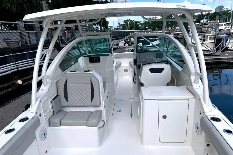 Slide: The Image of 2023 Pursuit DC 266 Dual Console boat interior with seating and helm, docked at marina. - 10