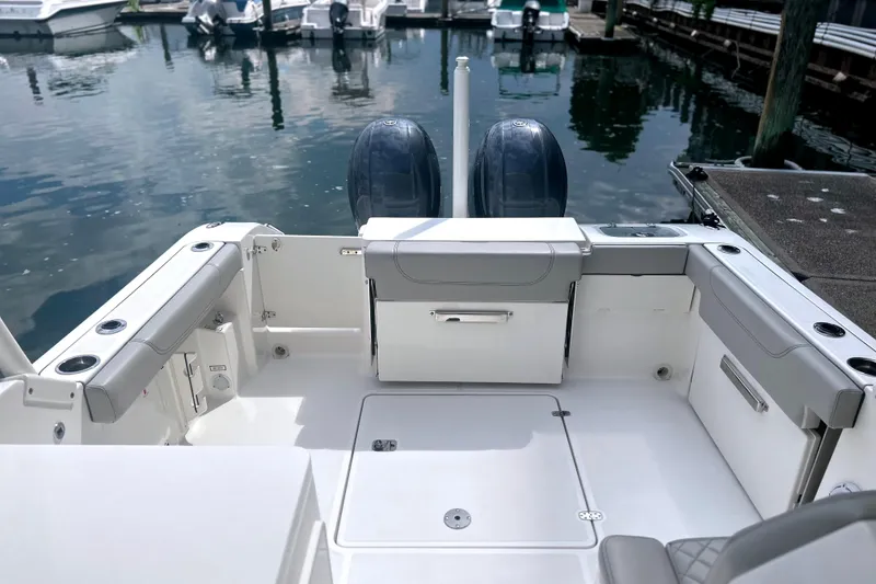 Slide: The Image of 2023 Pursuit DC 266 Dual Console boat interior with twin engines at a marina. - 12