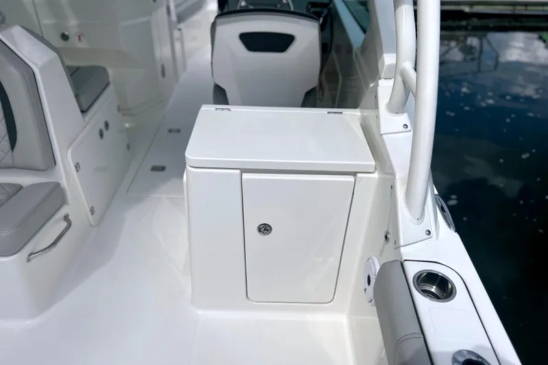Slide: The Image of 2023 Pursuit DC 266 Dual Console interior with seating and storage, docked by water. - 15