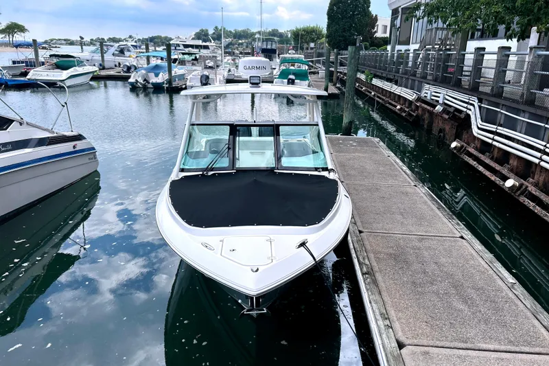 Slide: The Image of 2023 Pursuit DC 266 Dual Console boat docked at marina, calm water reflections. - 3