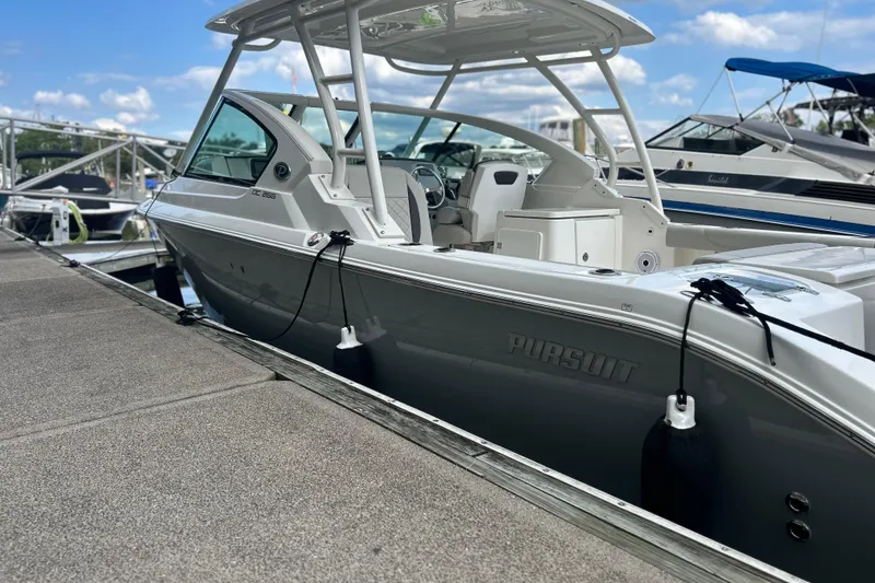 Slide: The Image of 2023 Pursuit DC 266 Dual Console boat docked at marina under clear sky. - 4