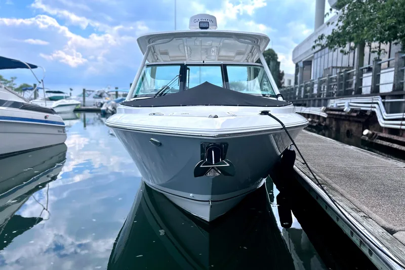 Slide: The Image of 2023 Pursuit DC 266 Dual Console boat docked at marina, reflecting on calm water. - 6