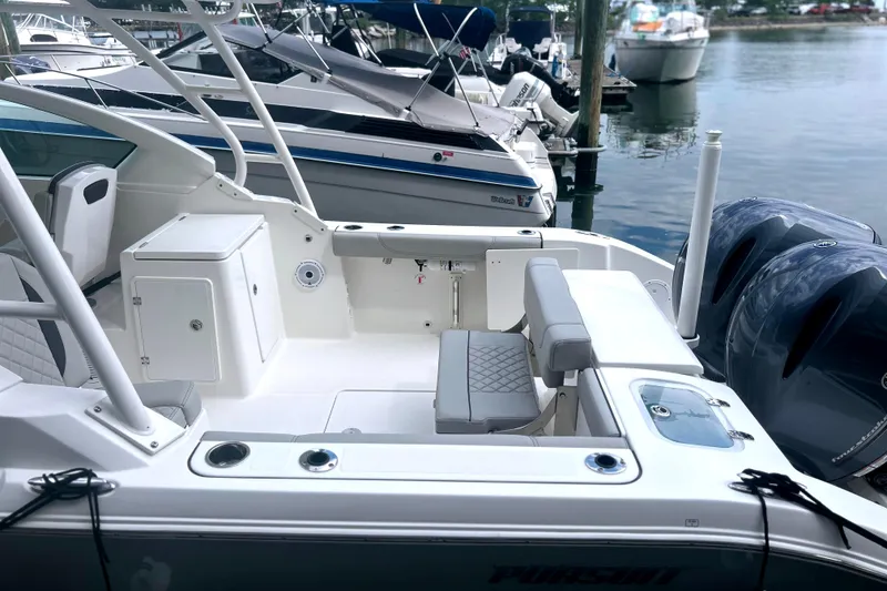 Slide: The Image of 2023 Pursuit DC 266 Dual Console boat docked, featuring spacious seating and dual engines. - 9