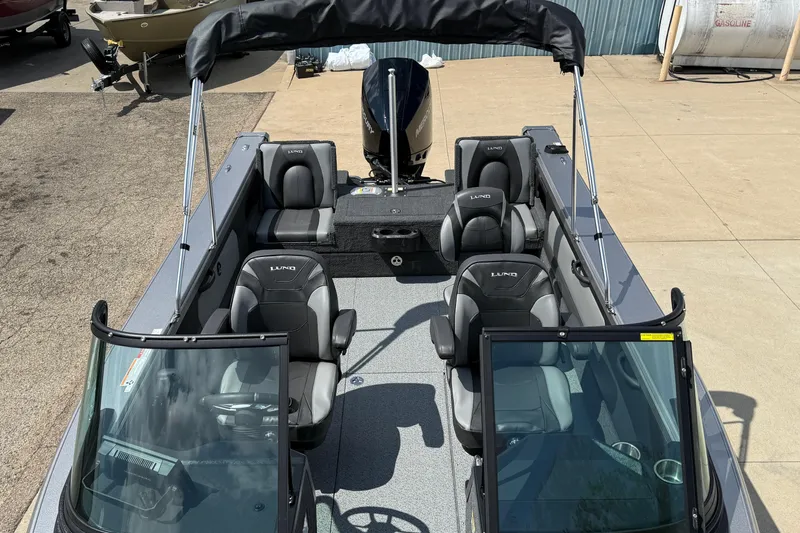 Slide: The Image of 2026 Lund 1975 Tyee boat interior with seating and windshield, docked outdoors. - 11