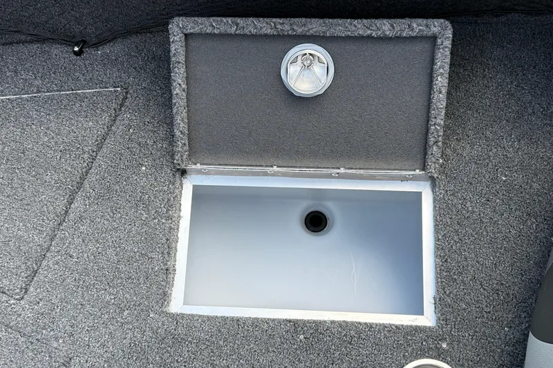 Slide: The Image of Open storage compartment in 2026 Lund 1975 Tyee boat, featuring gray carpeted interior. - 22