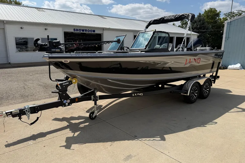 Slide: The Image of 2026 Lund 1975 Tyee boat on trailer outside showroom, featuring sleek design and modern features. - 3