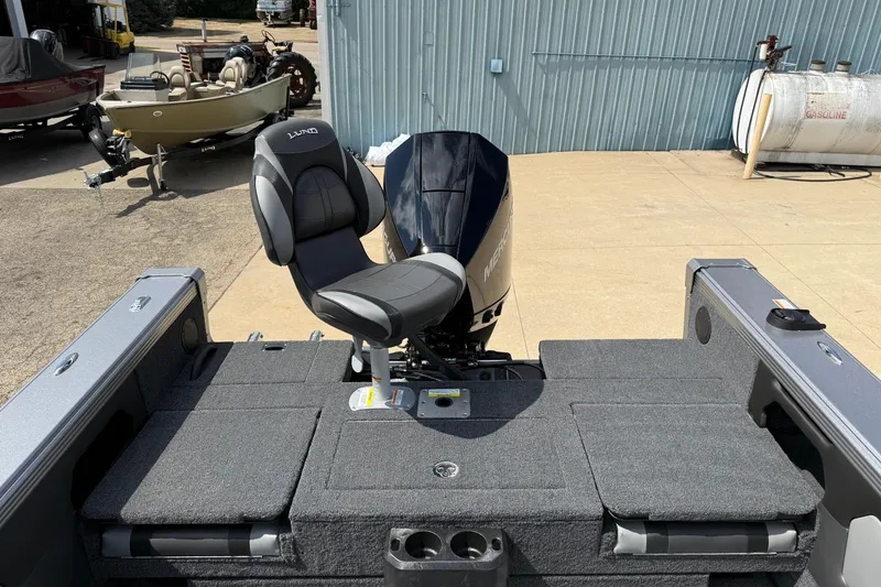 Slide: The Image of 2026 Lund 1975 Tyee boat with Mercury engine and cushioned seating, parked outdoors. - 33