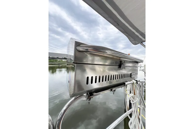 Slide: The Image of Stainless steel grill on 1984 Trintella 42 yacht, docked by calm waters under cloudy sky. - 11