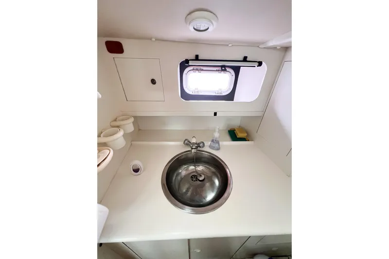 Slide: The Image of Compact bathroom sink area in a 1984 Trintella 42 yacht, featuring a round basin and porthole. - 33