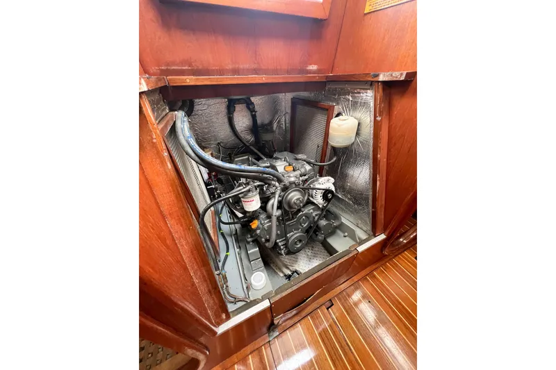 Slide: The Image of Engine compartment of a 1984 Trintella 42 sailboat, showcasing mechanical components and wooden interior. - 75
