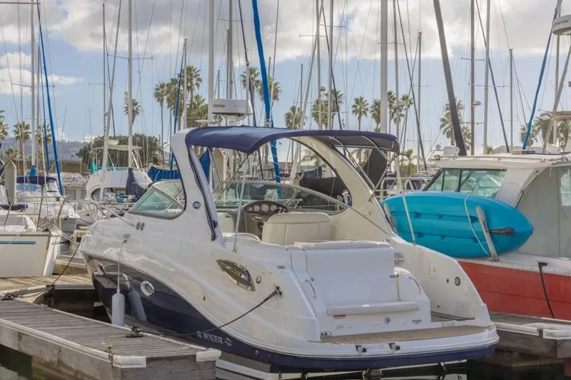 The Image of 2013 Rinker 290 Express Cruiser docked at a marina with sailboats. - 0