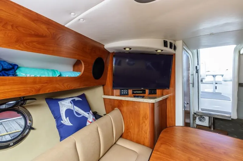 Slide: The Image of 2013 Rinker 290 Express Cruiser interior with TV, wood finish, and cozy seating. - 16