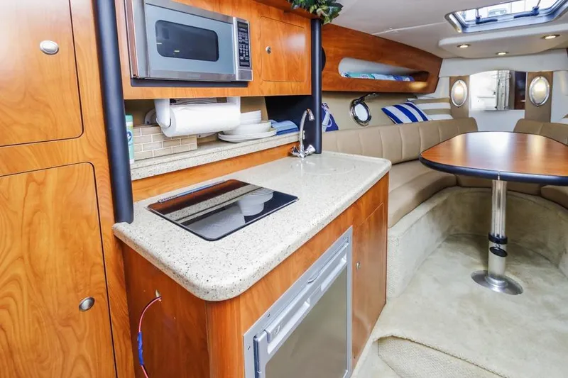 Slide: The Image of 2013 Rinker 290 Express Cruiser interior with kitchenette and seating area. - 19