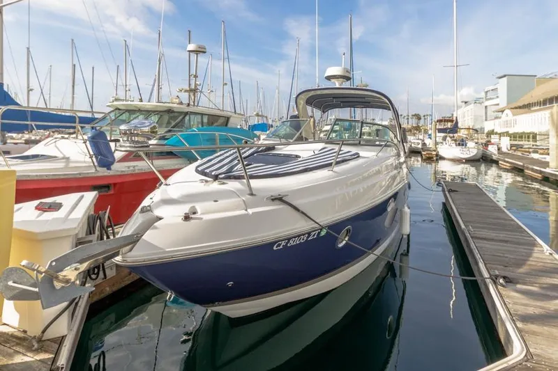 Slide: The Image of 2013 Rinker 290 Express Cruiser docked at marina, surrounded by sailboats. - 2