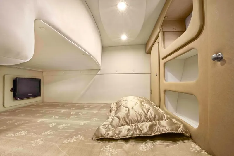 Slide: The Image of Manufacturer Provided Image: 2013 Rinker 290 Express Cruiser cabin interior with bed, pillow, and storage shelves. - 22