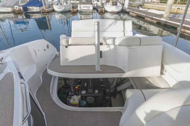 Slide: The Image of 2013 Rinker 290 Express Cruiser engine compartment with seating, docked at marina. - 23