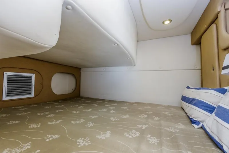 Slide: The Image of 2013 Rinker 290 Express Cruiser cabin interior with bed and striped pillow. - 26