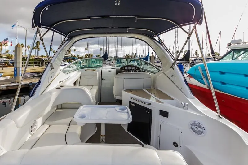 Slide: The Image of 2013 Rinker 290 Express Cruiser interior with seating, table, and helm at marina. - 5