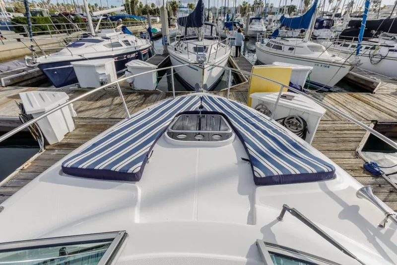 Slide: The Image of 2013 Rinker 290 Express Cruiser docked with striped cushions on deck. - 7